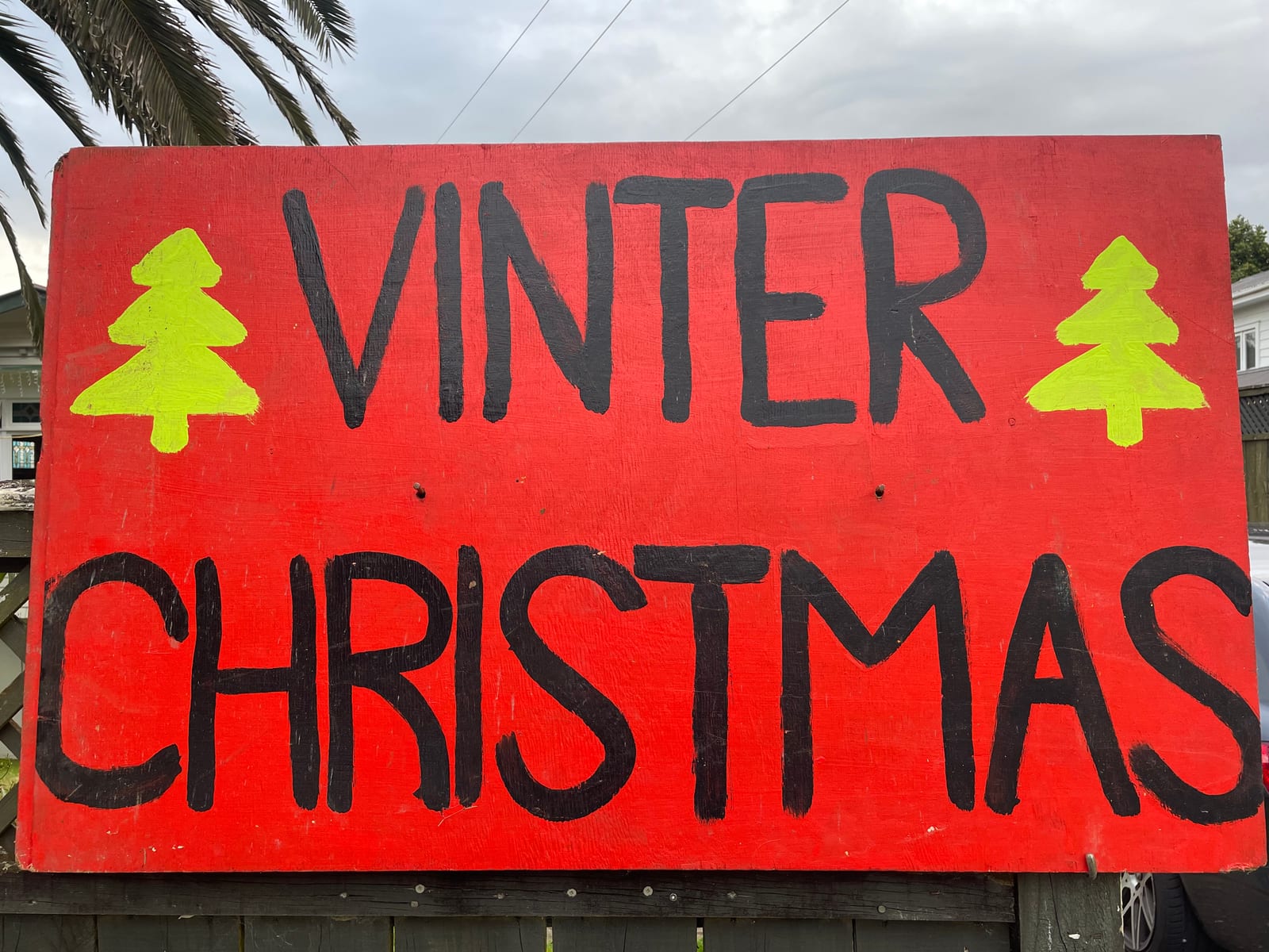 A hand-painted red Christmas tree sale sign reading 'Winter Christmas'